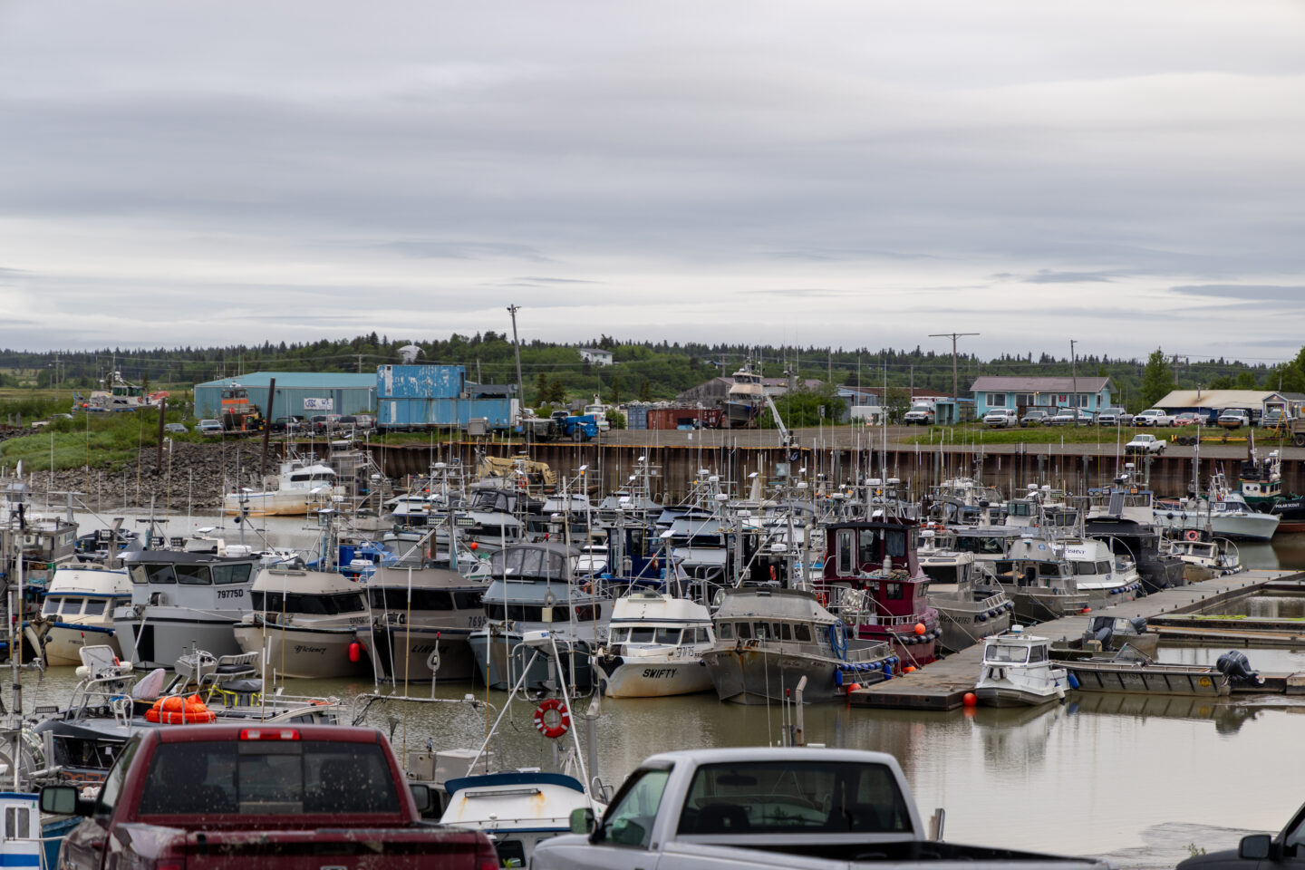 Crowded marina with rows of fishing boats docked along the pier under cloudy skies