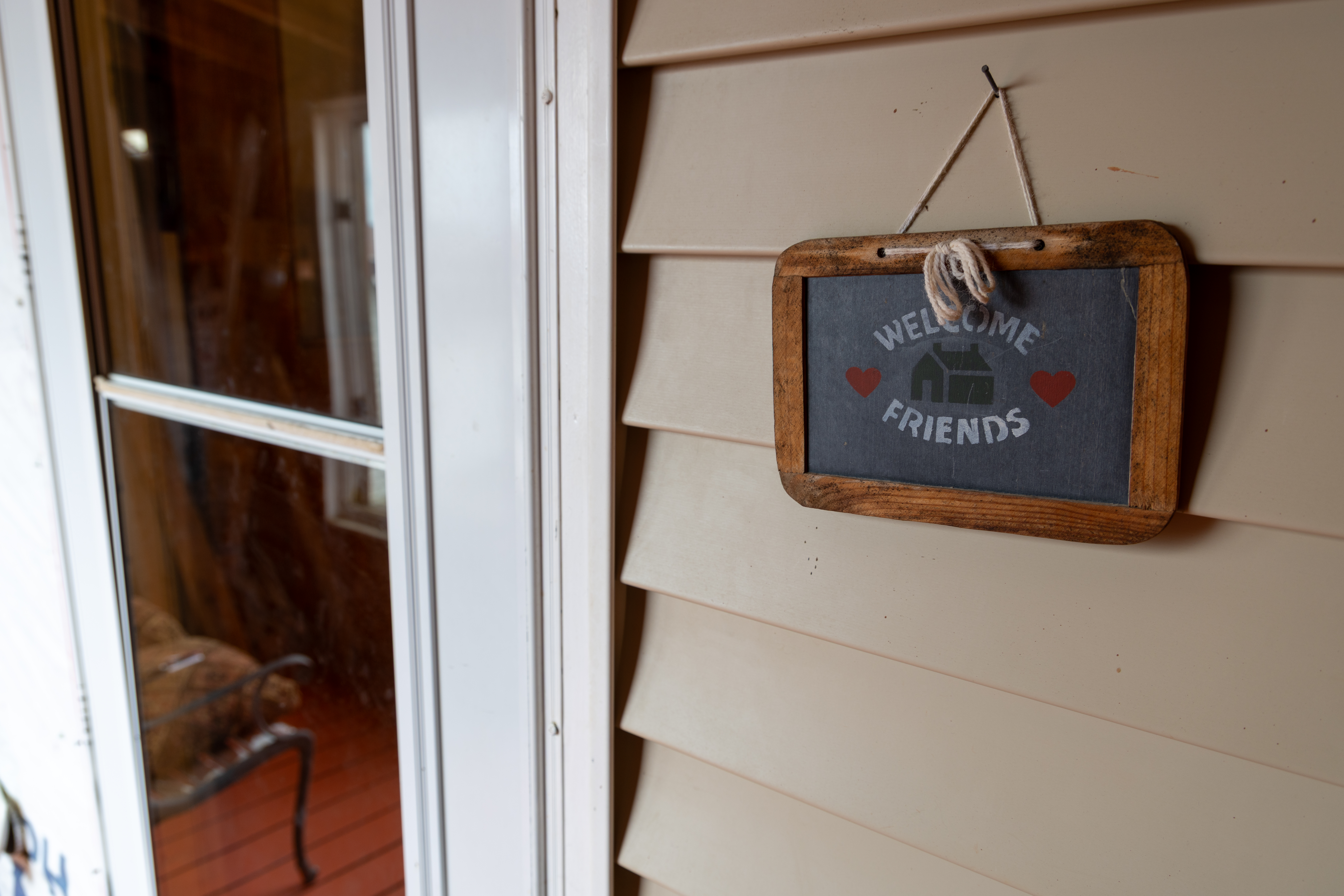 Small wooden sign by front door that says Welcome Friends with red hearts